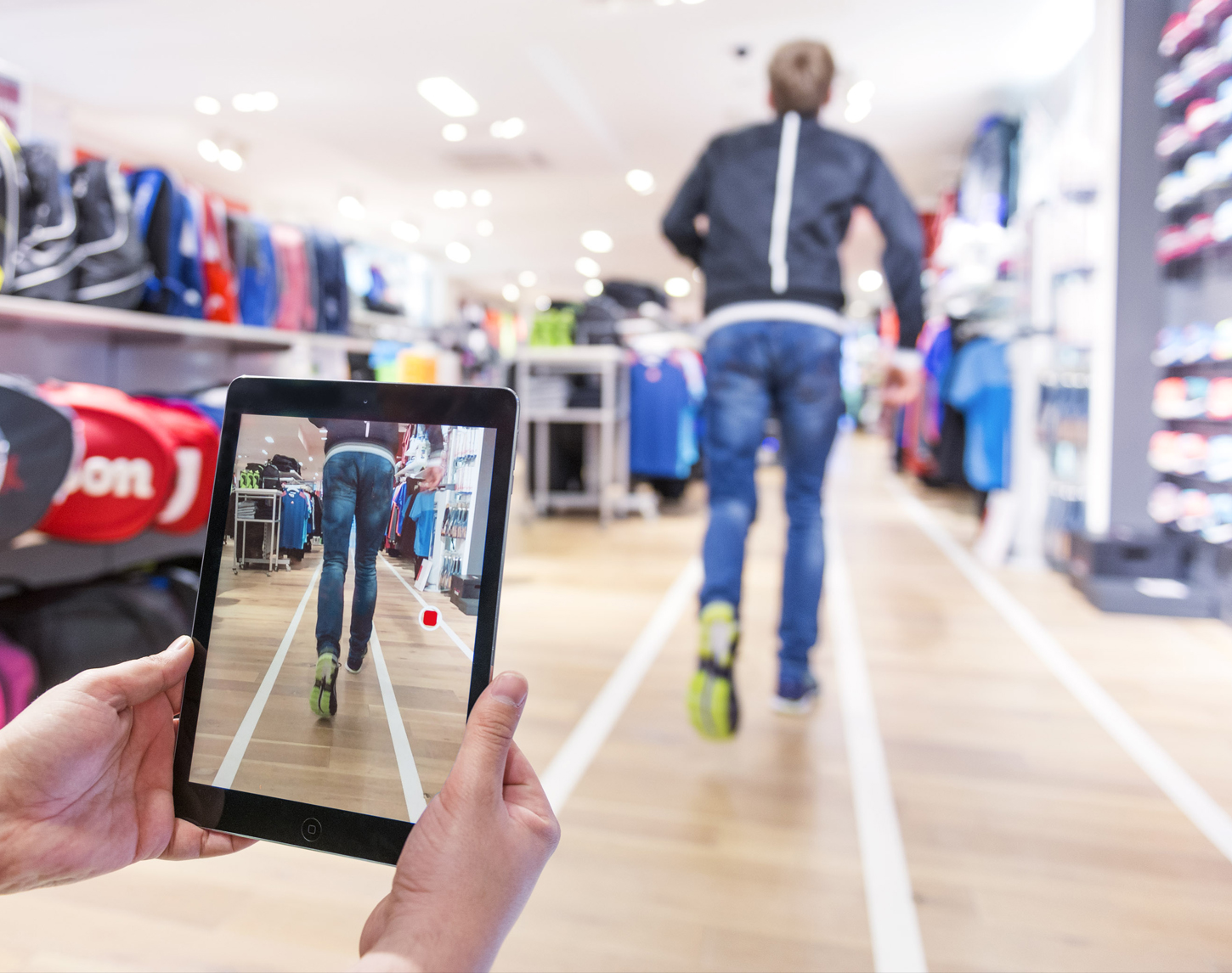 hardlopende man in winkel met tablet die filmt voor hardloopanalyse
