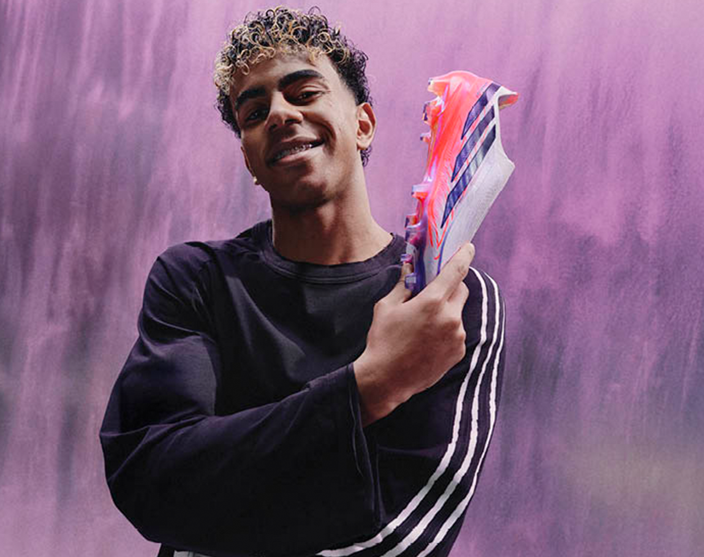 1 voetballer houdt 1 roze voetbalschoen omhoog