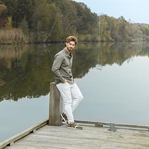 Model op brug met beige kleding en sneakers