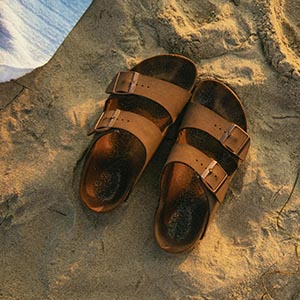 bruine herenslippers in het zand