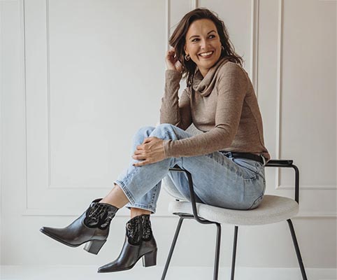 Dame op stoel met benen over elkaar en donkere westernlaarsjes