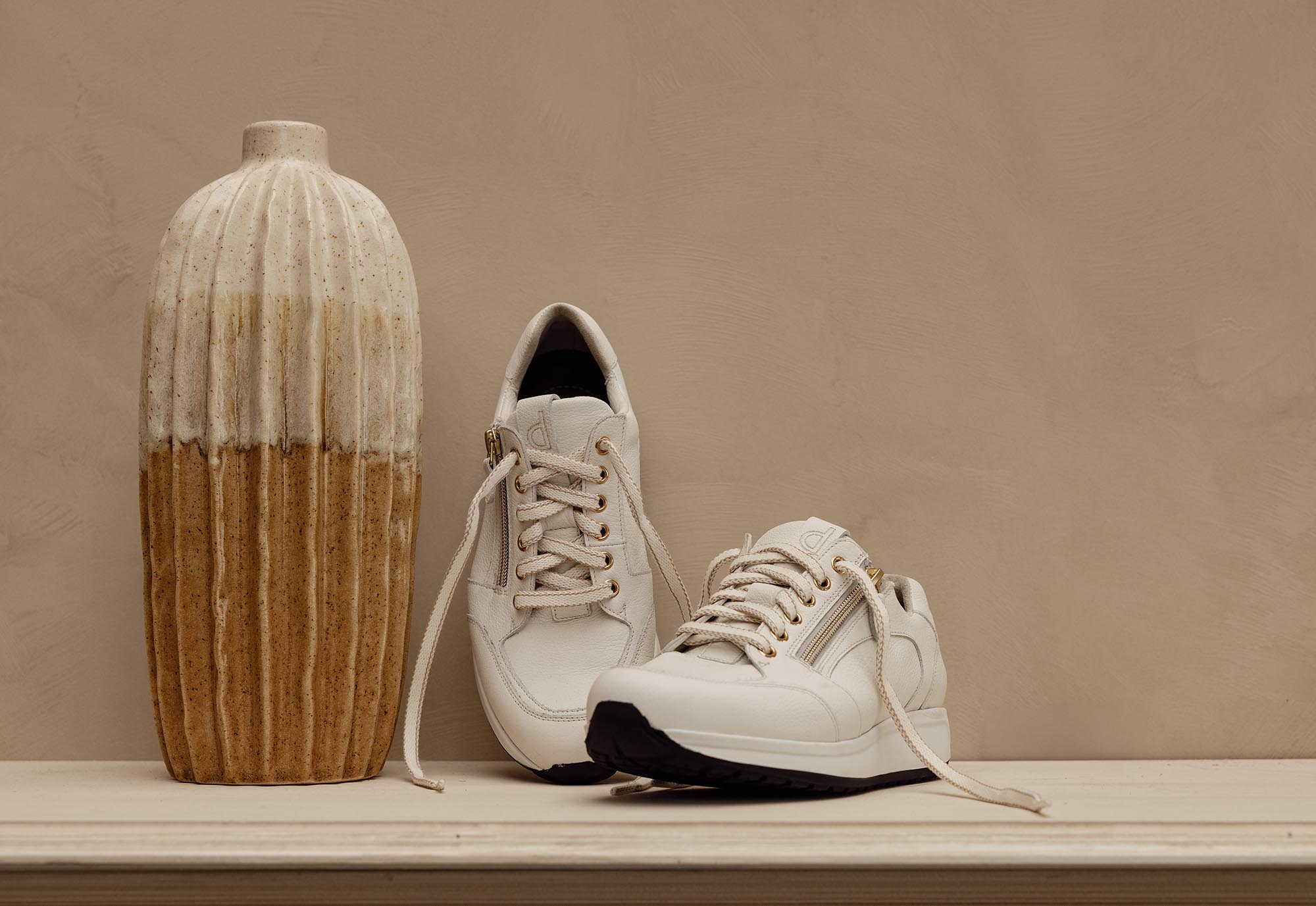 1 paar lichte sneakers voor bruine muur