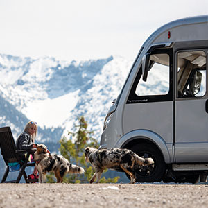 vrouw met 2 honden voor camper in de sneeuw