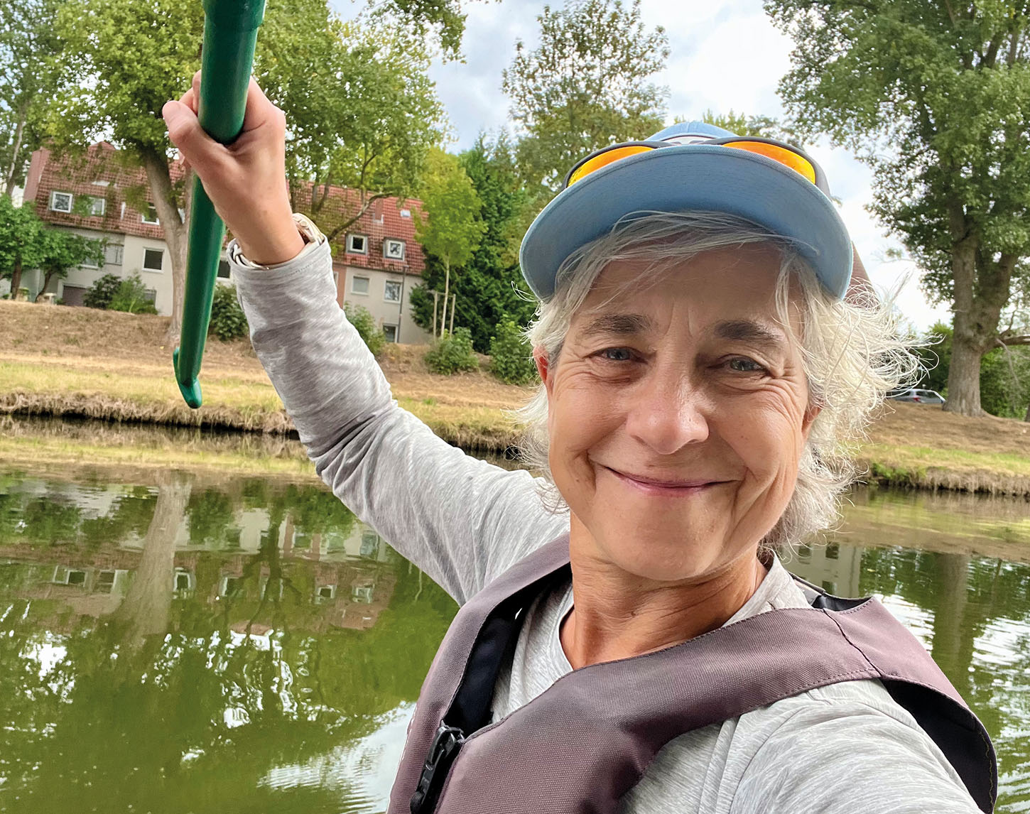 vrouw met op de achtergrond een rivier en een boerderijachtig huis