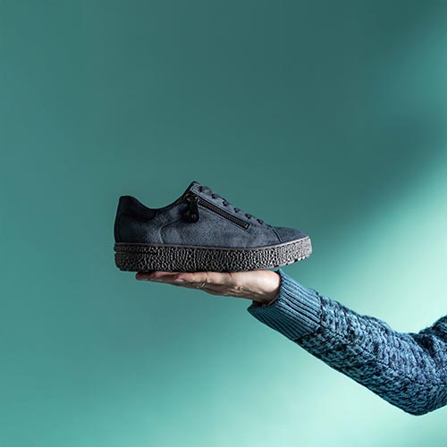 hand die blauwe dames veterschoenen op houdt