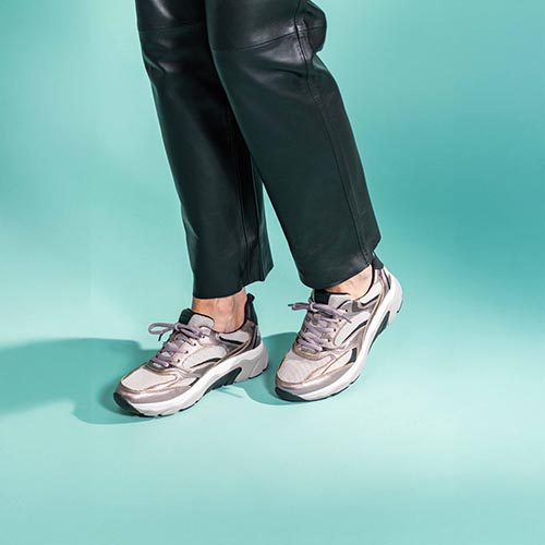 2 benen met zwarte broek en paars tint metallic sneakers
