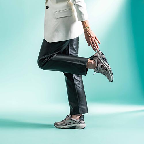 2 damesbenen 1 daarvan iets omhoog met paars tint metallic sneakers