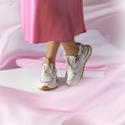 Damesbenen met sneakers en roze lange rok