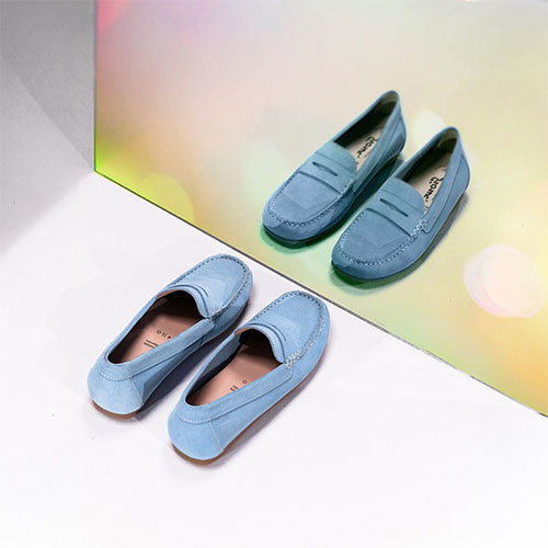 dame zittend op grond voor oranje achtergrond met zwarte loafers aan