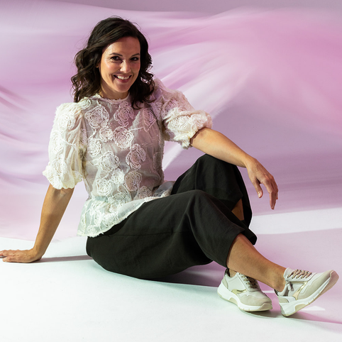 dame die rood bruin metallic sneaker omhoog houdt